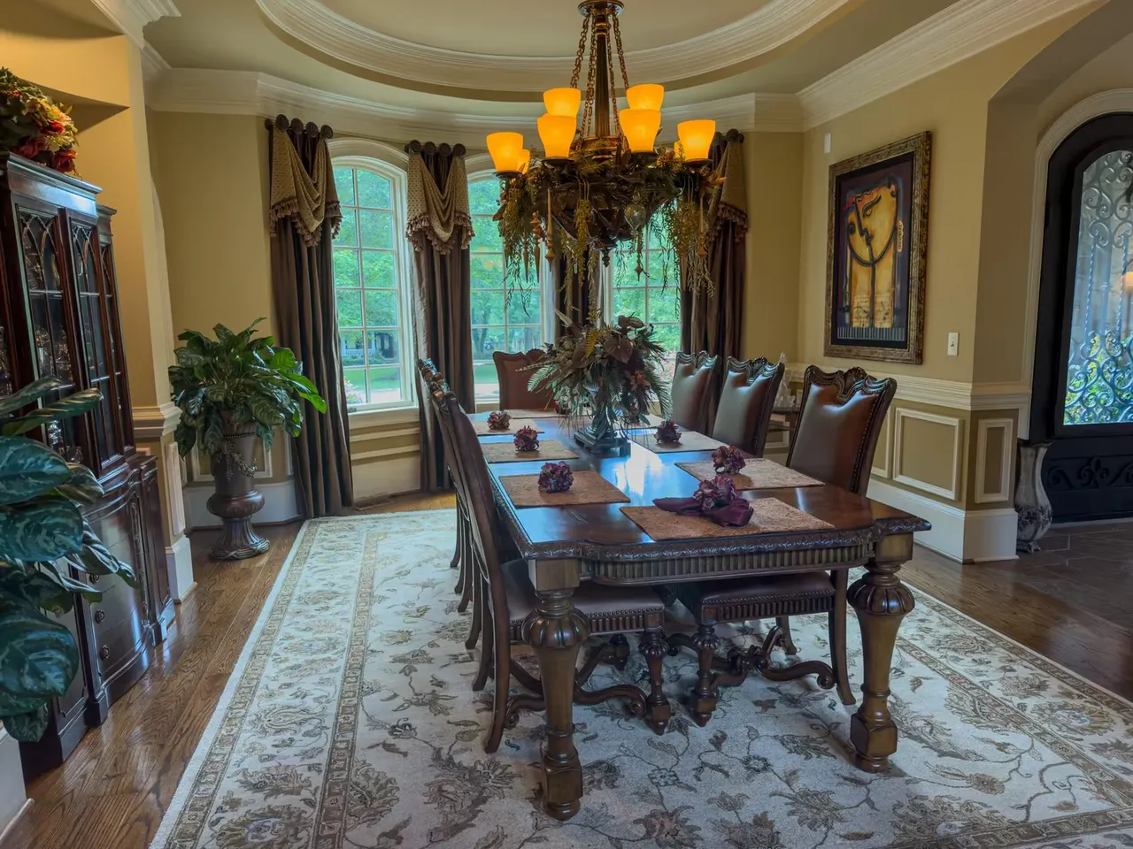 Dining room under the chandelier, arched windows to the lawn