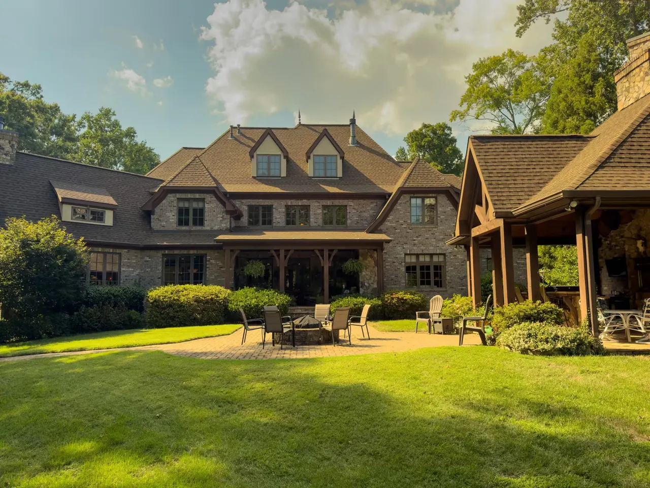 Rear elevation from the lawn under afternoon clouds