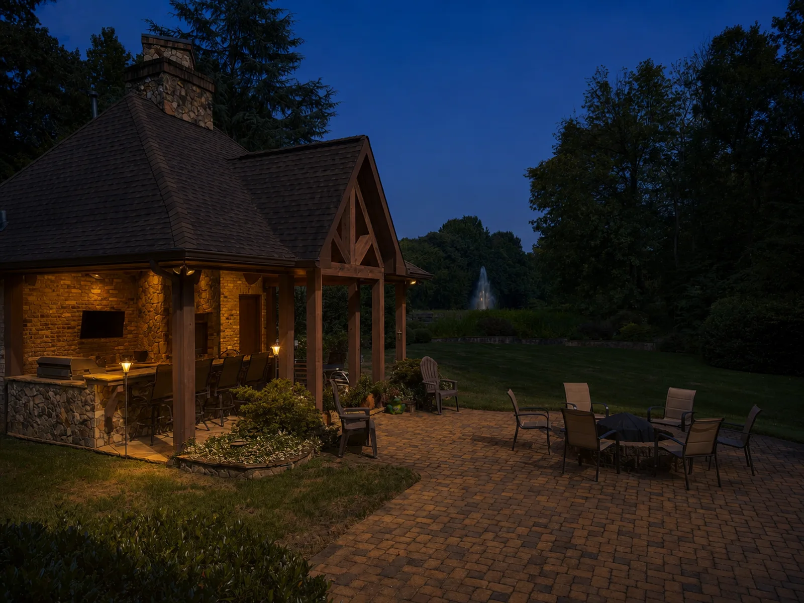 AI evening lighting interpretation of the same view of a stone and timber pavilion beside a garden terrace