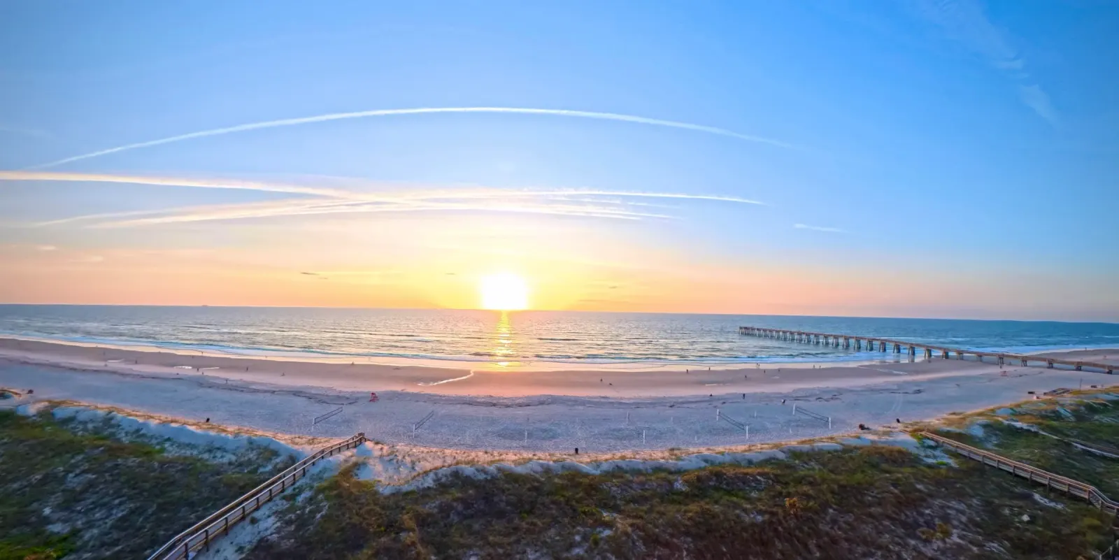 Sunrise over the ocean, beach boardwalks and a pier, photographed by Paul Mattson
